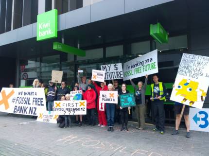Group of campaigners outside Kiwibank branch in Christchurch, holding signs calling for Kiwibank to go fossil free