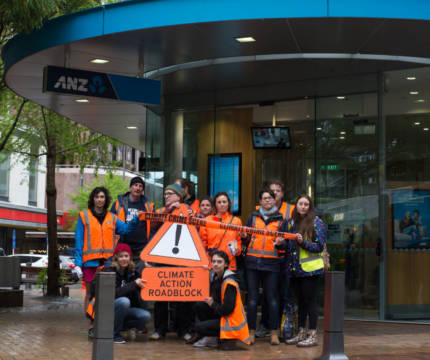 350 Wellington campaigners at an action outside ANZ holding signs reading "climate action roadblock"