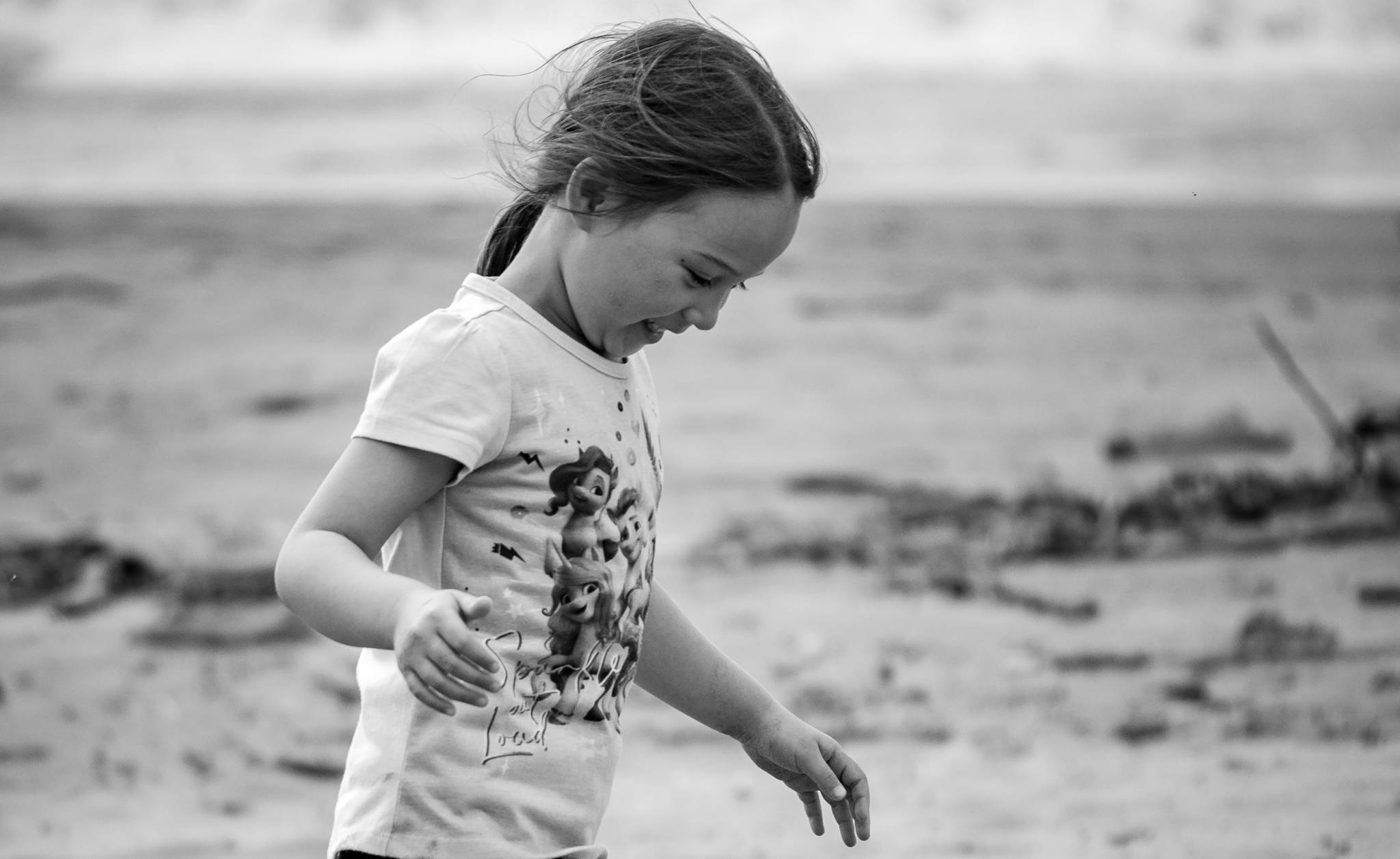Image of a small girl playing on the beach in the sand