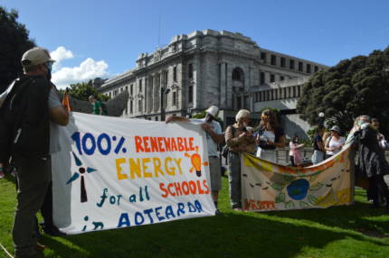 People holding a 100% Renewable Energy for all schools in Aotearoa banner outside Parliament