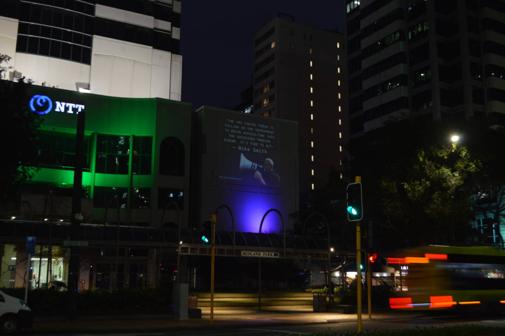 night time projections on building with the quote from Mike Smith + photo of him yelling into a microphone 