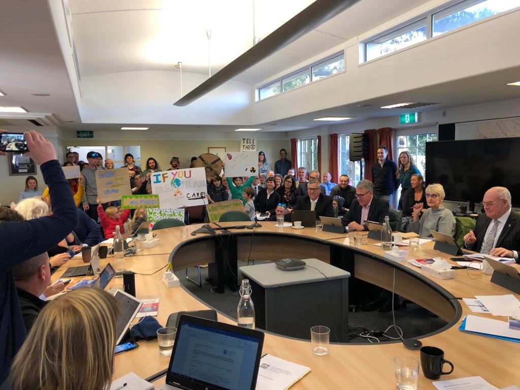 Photo of activists holding banners in a council meeting