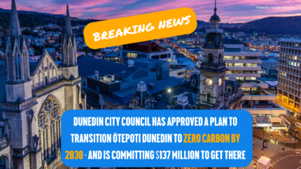 Text reads "Breaking news" on the top of the image with an orange background. Bottom text reads" Dunedin City Council has approved a plan to transition Ōtepoti Dunedin to Zero Carbon by 2030 - and is committing to $137 million to get there" highlighted in blue. Background image is an aerial view of Ōtepoti at night.