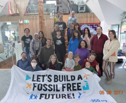 Group of around 20+ 350 volunteers, staff, and board members pose for a photo inside the BGI upstairs office behind the ‘Let’s build a fossil free future!’ banner.